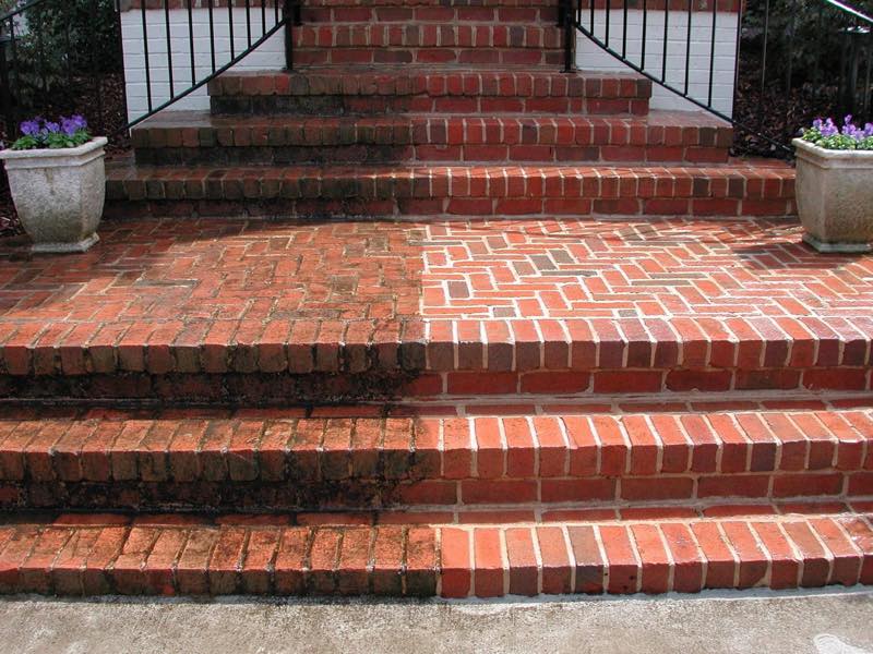 Brick front steps mid-clean, the left half still dark with dirt and algae, the right half back to red brick