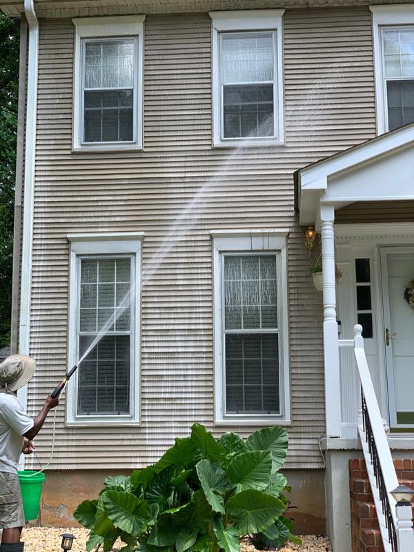 Soft washing vinyl siding, a clean stripe showing where the spray has reached